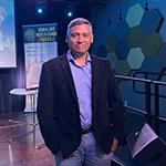 Rajiv Menon, founder of the Orlando Innovation League, poses in front of a stage at the Full Sail Treehouse.